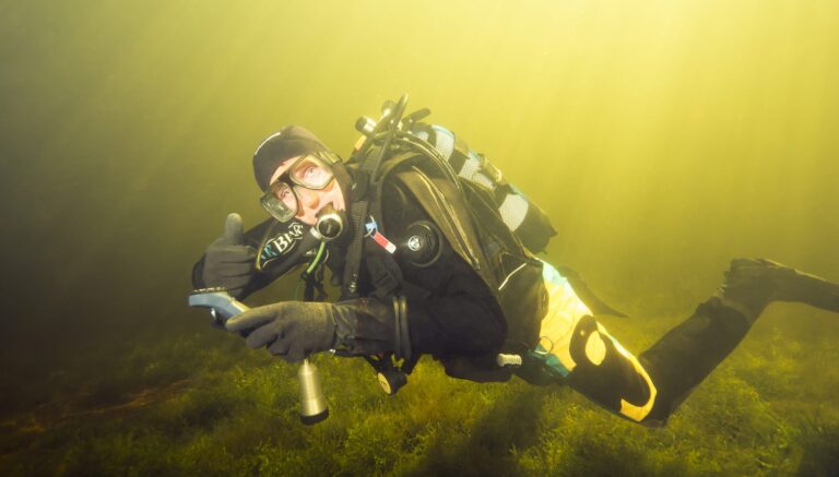 Duiker met lamp en uitrusting in groen water